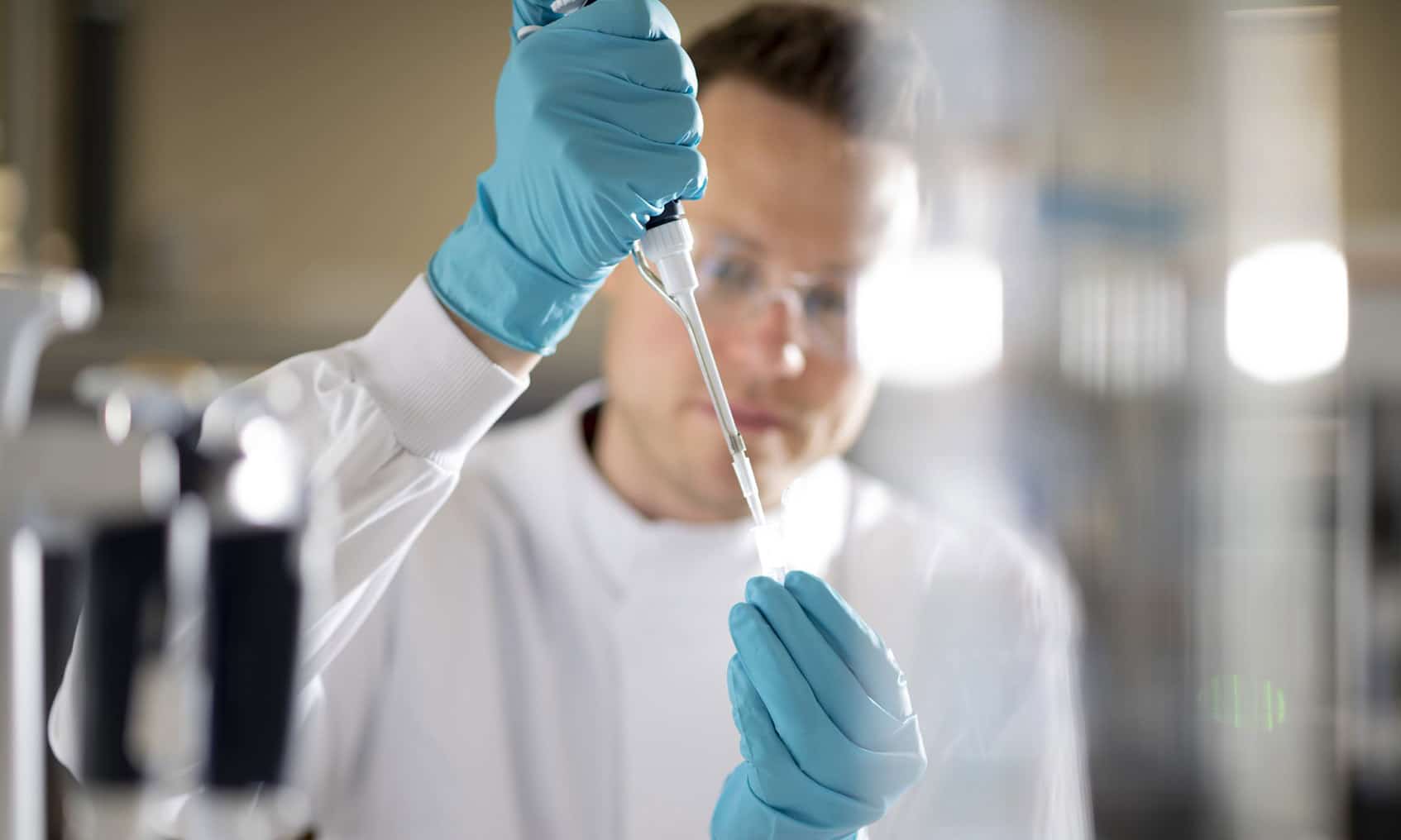Scientist wearing PPE in lab, carrying out an experiment