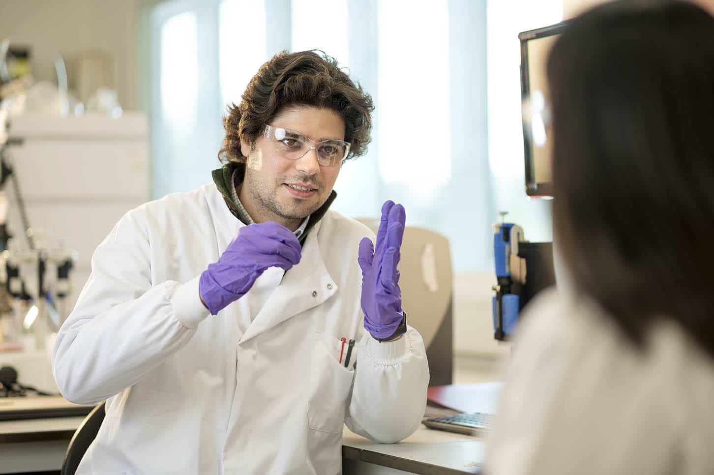 Scientists wearing PPE whilst in conversation in lab