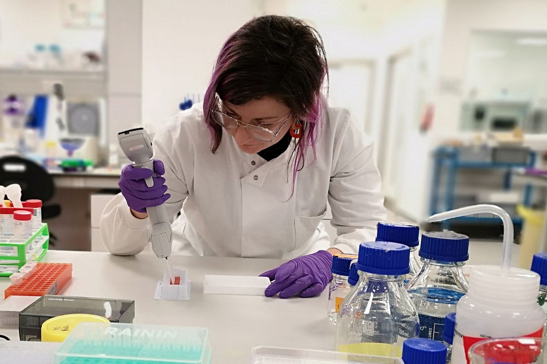 Scientist in our lab, wearing PPE and carrying out an experiment