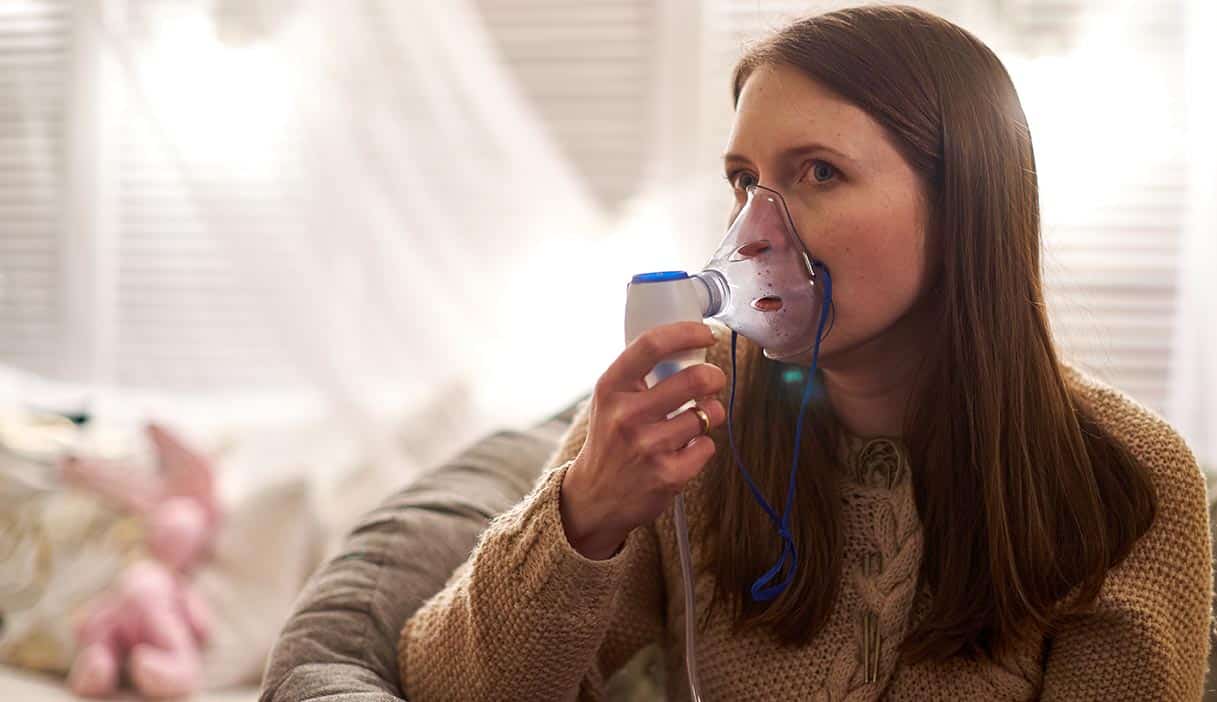 Woman uses a nebulizer at home.