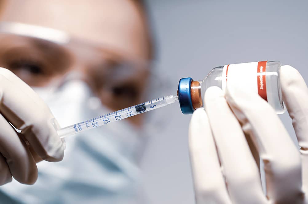 Doctor holding a syringe with a single bottle vial of Covid-19