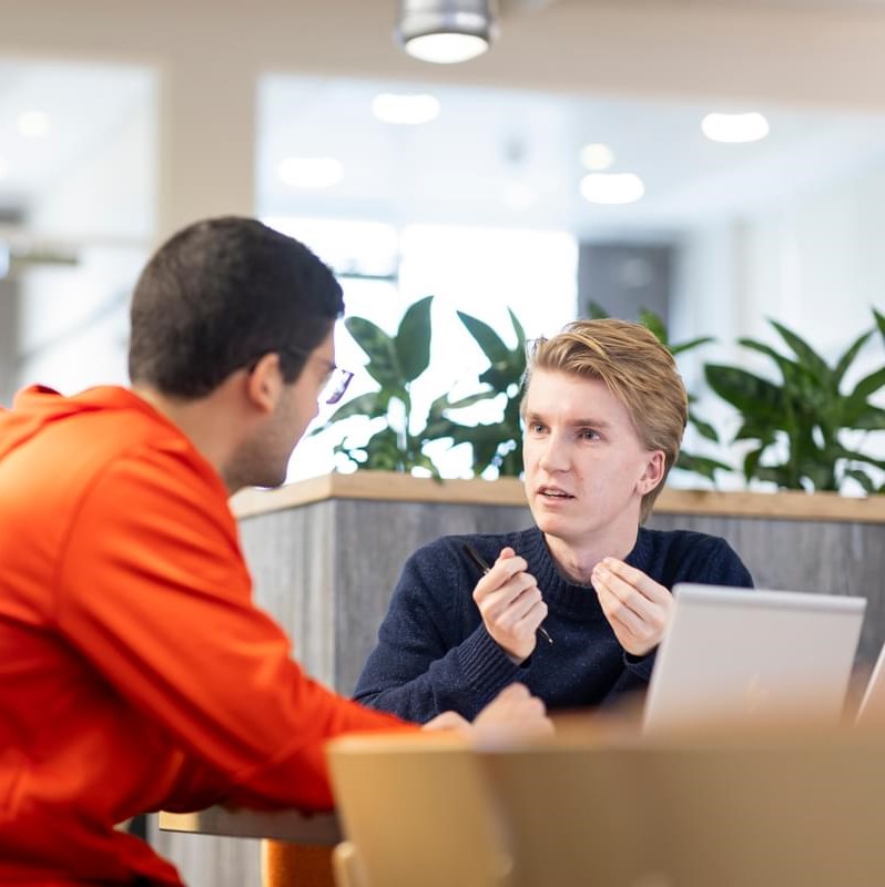 Two male LifeArc colleagues sit having a meeting in the communal space at the Stevenage lab site