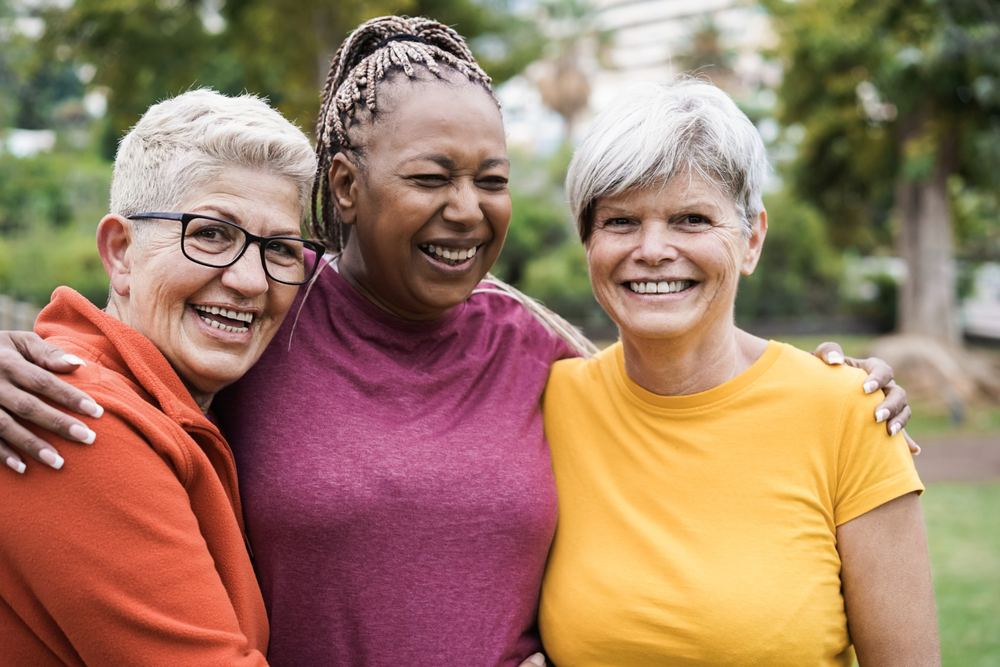 Group of three ladies wit their arms around each other smiling for the camera and laughing