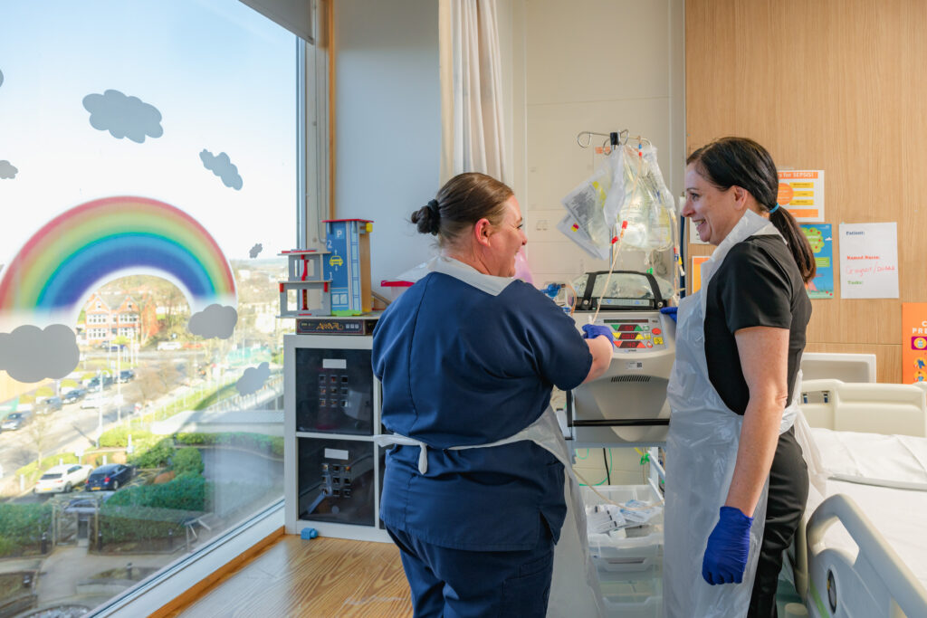 Louise Oni, Centre lead for the LifeArc-Kidney Research UK Centre for Rare Kidney Diseases, smiling and talking to a nurse at Alder Hey Children's hospital