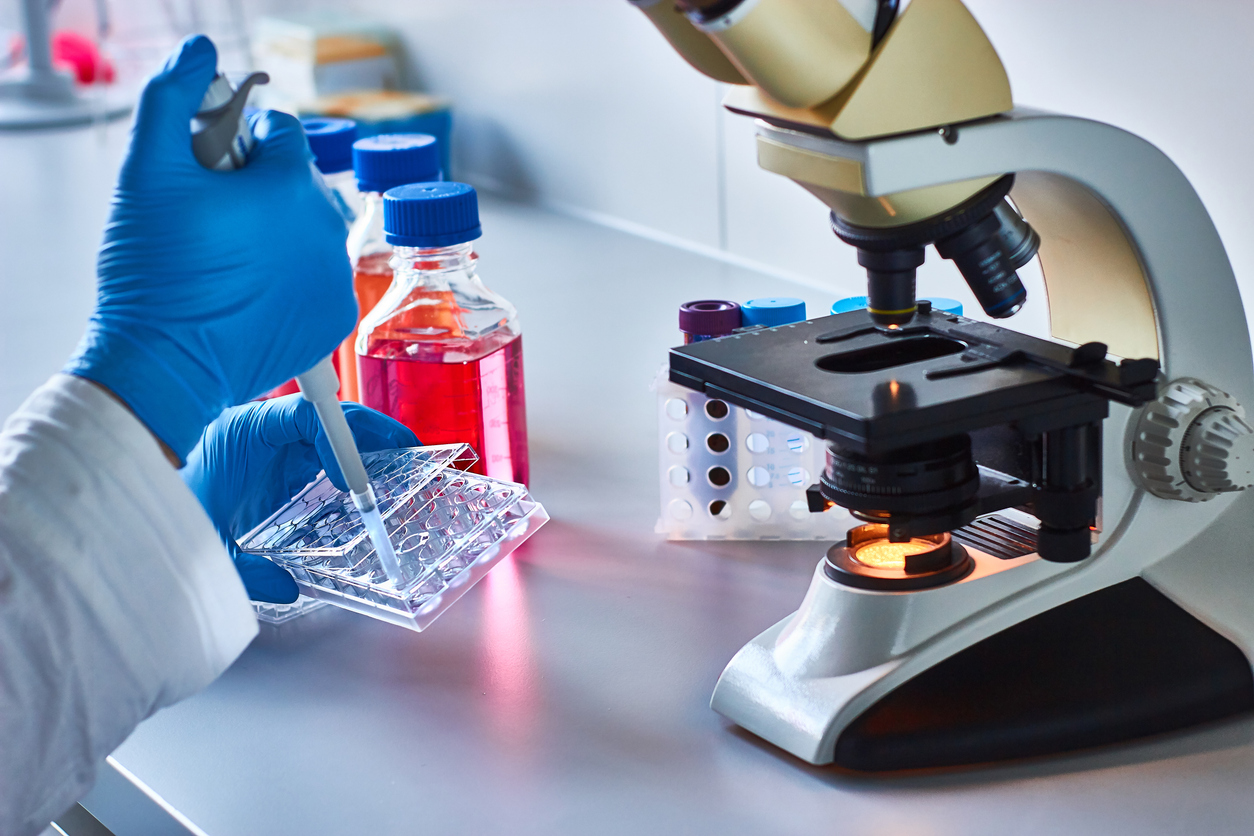 Scientist pipetting research samples by the microscope