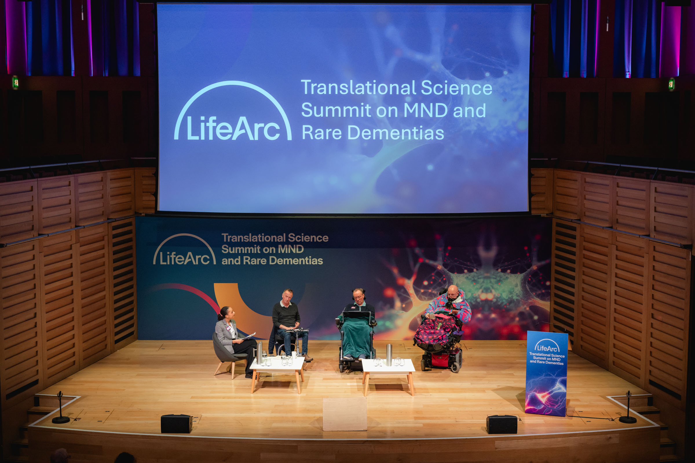 Panel discussion at the LifeArc Translational Science Summit on MND and Rare Dementias. 3 expert speakers who have MND are on stage with a LifeArc employee chairing the discussion