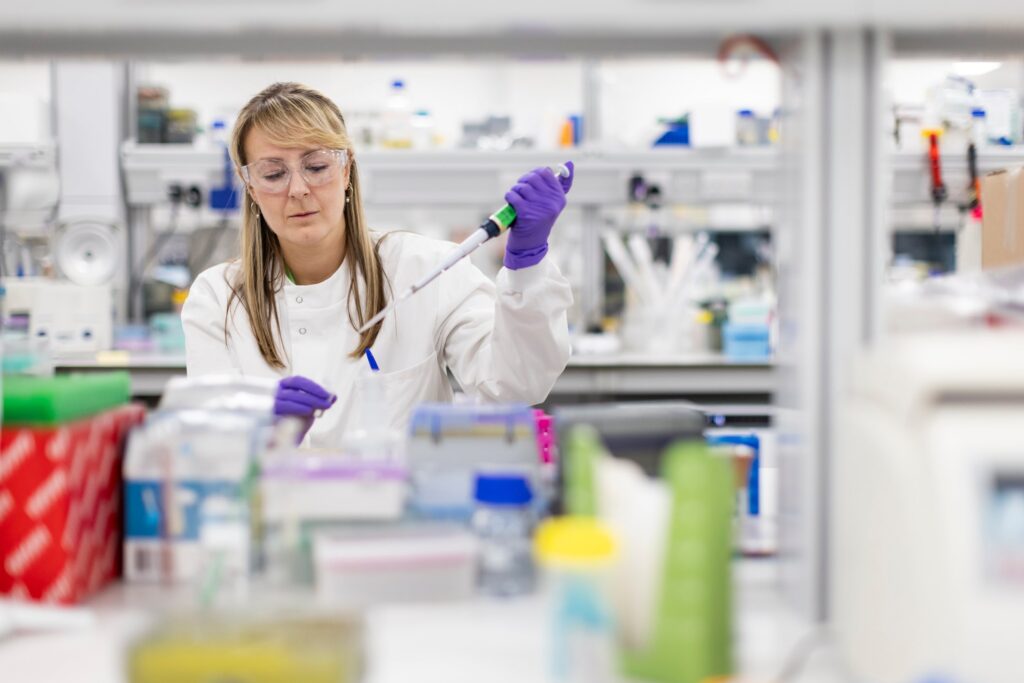 A female LifeArc scientist pipettes liquid into a tube.