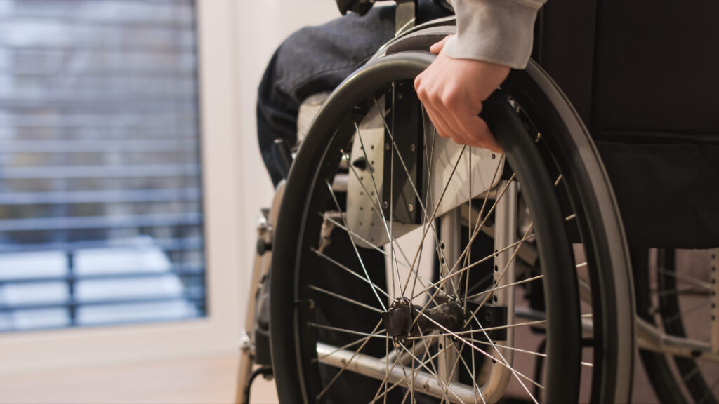 Close up of wheel of a wheelchair with a man sat in it