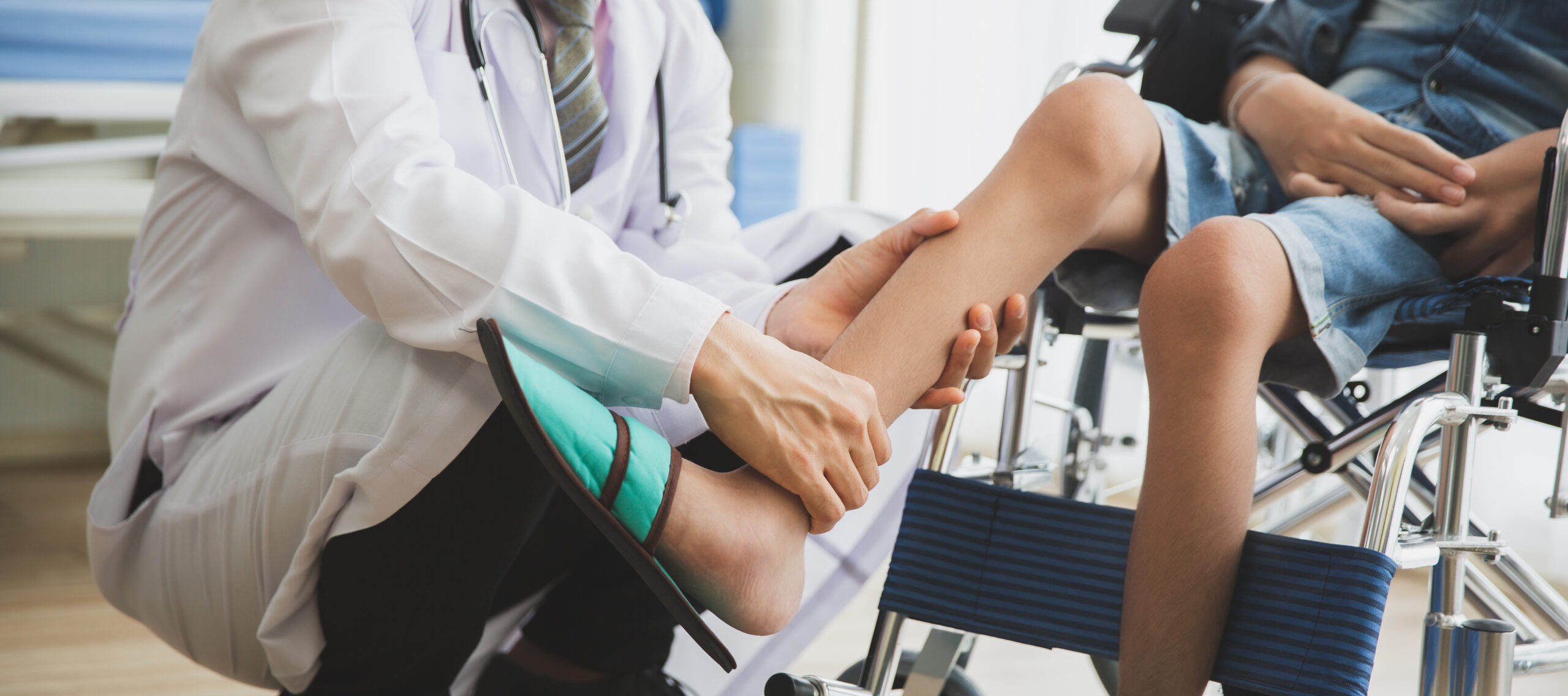 Doctor performs joint checks on person with Muscular dystrophy by touching their calf.