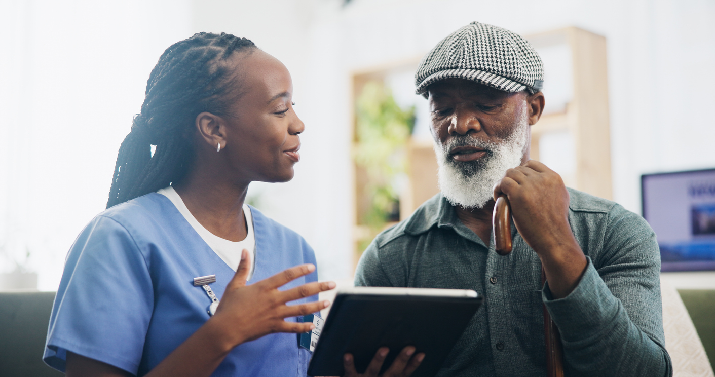 A female healthcare practitioner consulting with an elderly male patient