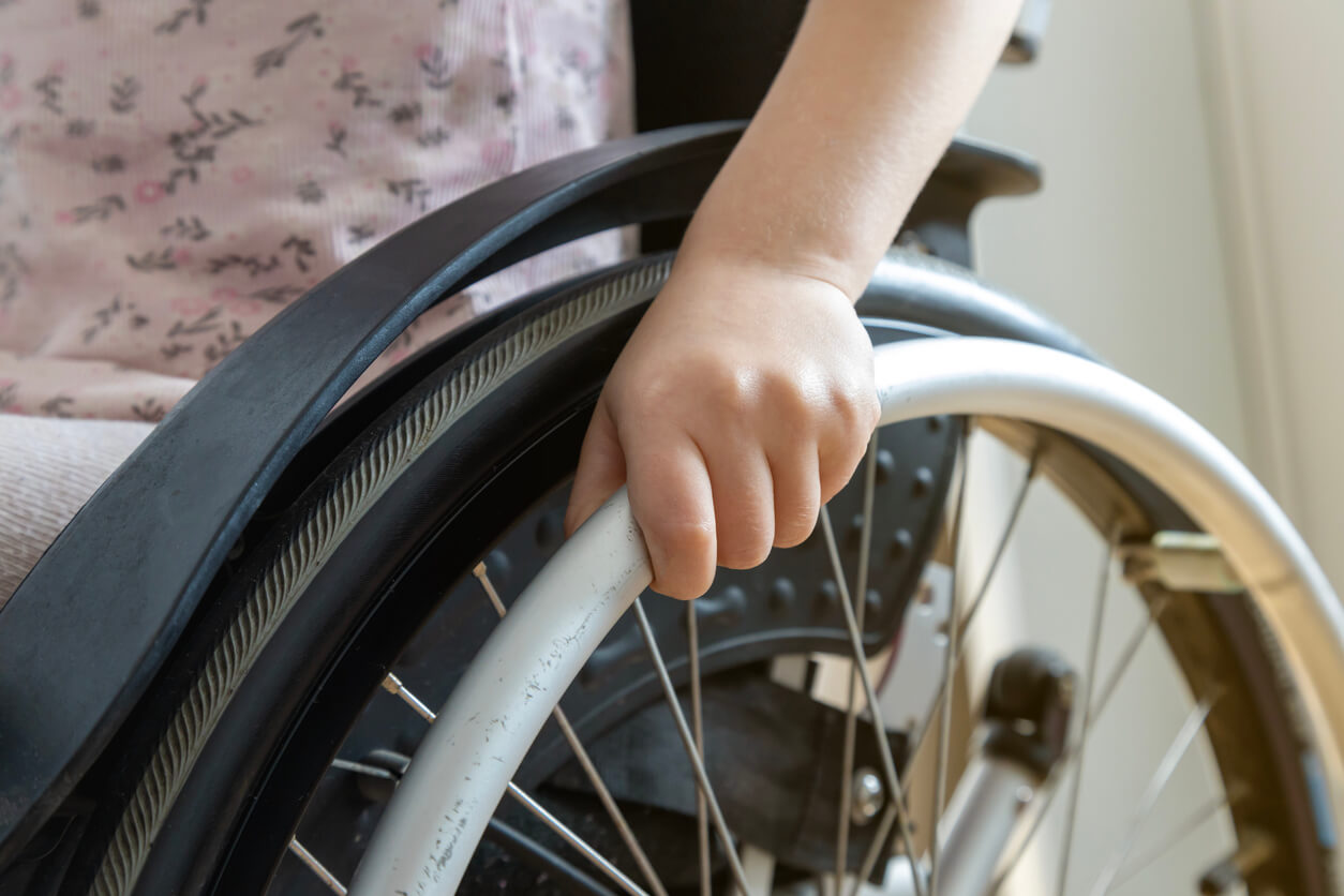 Close-up of a child's hand on the wheel of a wheelchair