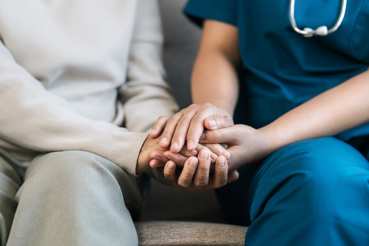 A female nurse caregiver holds hands to encourage and comfort an elderly woman. For care and trust in nursing homes for people of retirement age Caregiver helping elderly woman provides medical advice