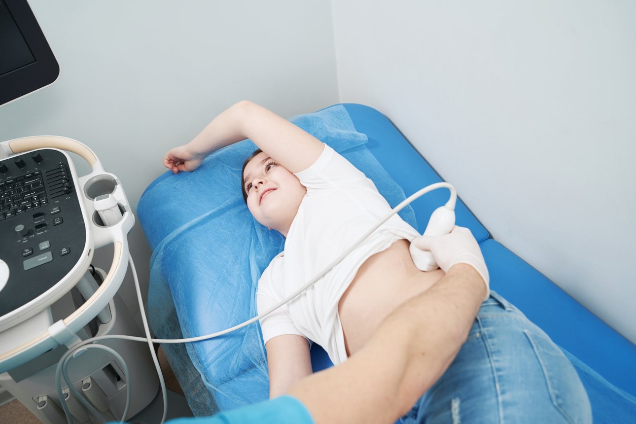 Young girl lying on a hospital bed undergoing kidney ultrasound