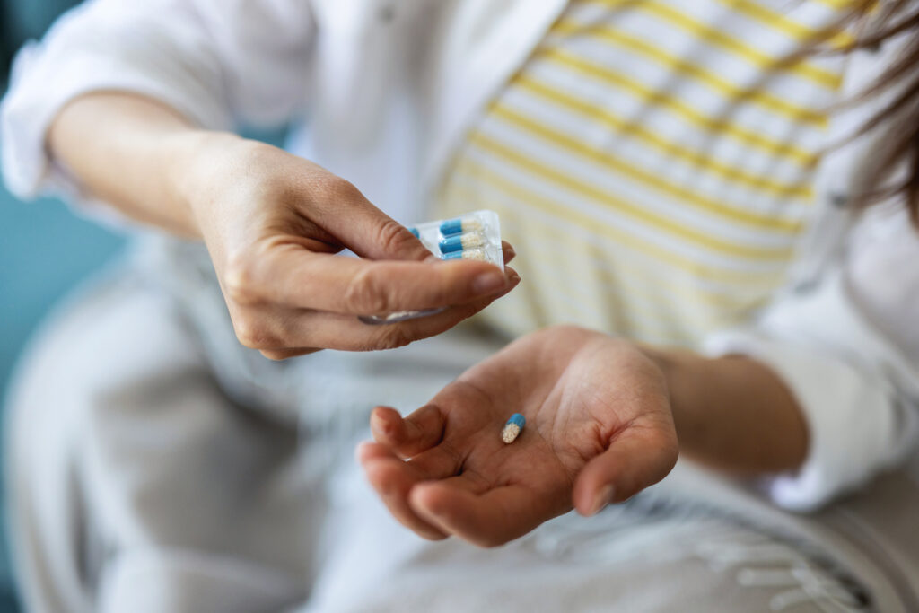Person's hands popping out an oral antibiotic from a packet.